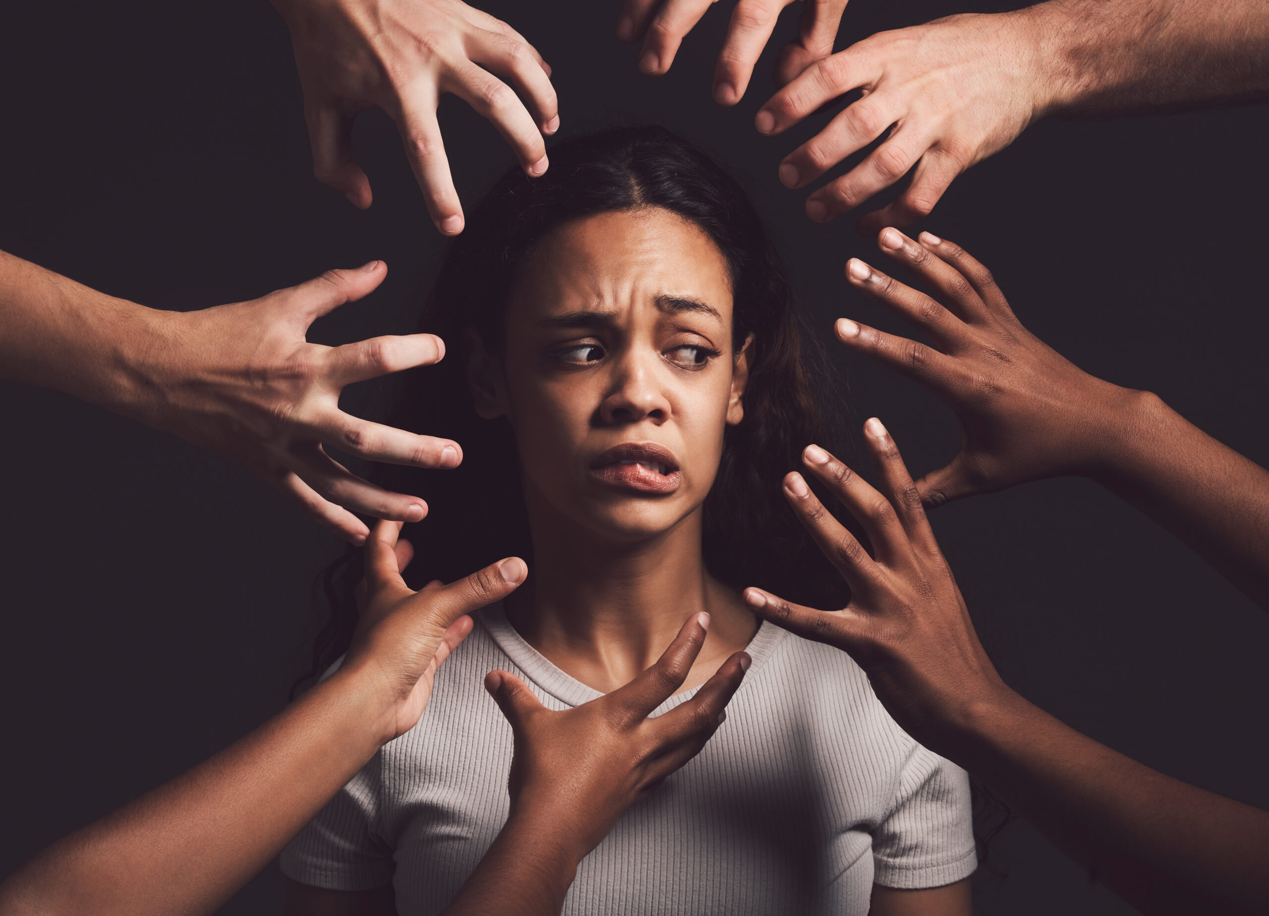 Shot of hands grabbing a young womans against a dark background.