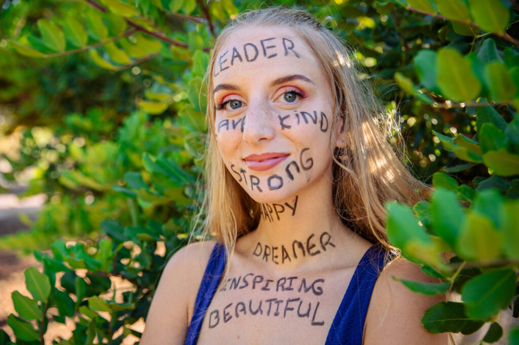 Portrait of a young woman with motivational words written on her skin, confident woman empowered
